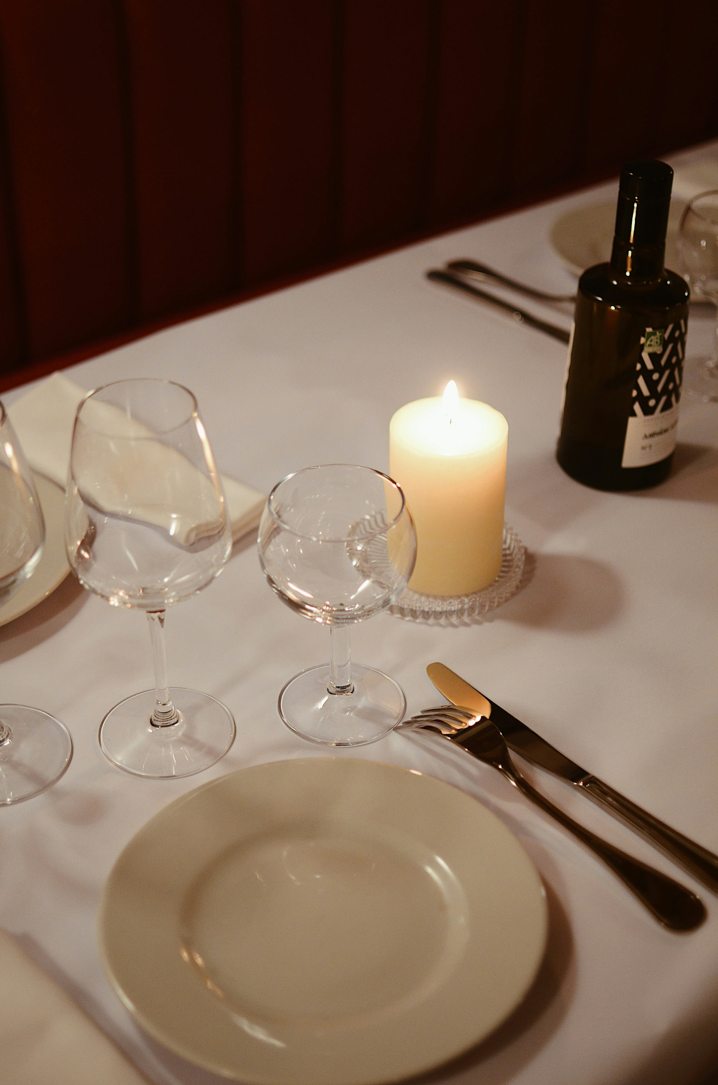 Candlelit dinner table set with wine glasses and elegant cutlery.