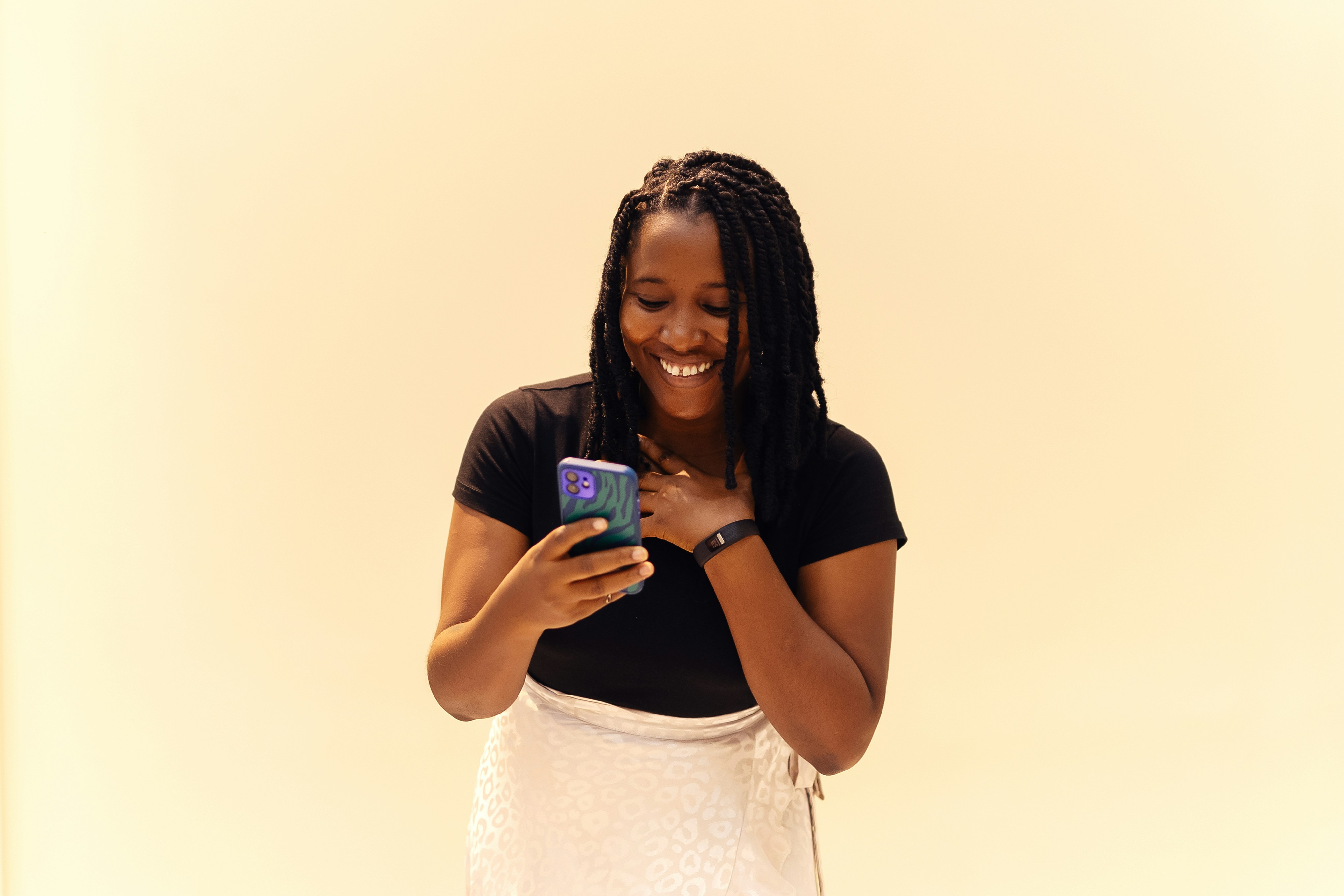 Woman smiling while using her smartphone against a neutral background