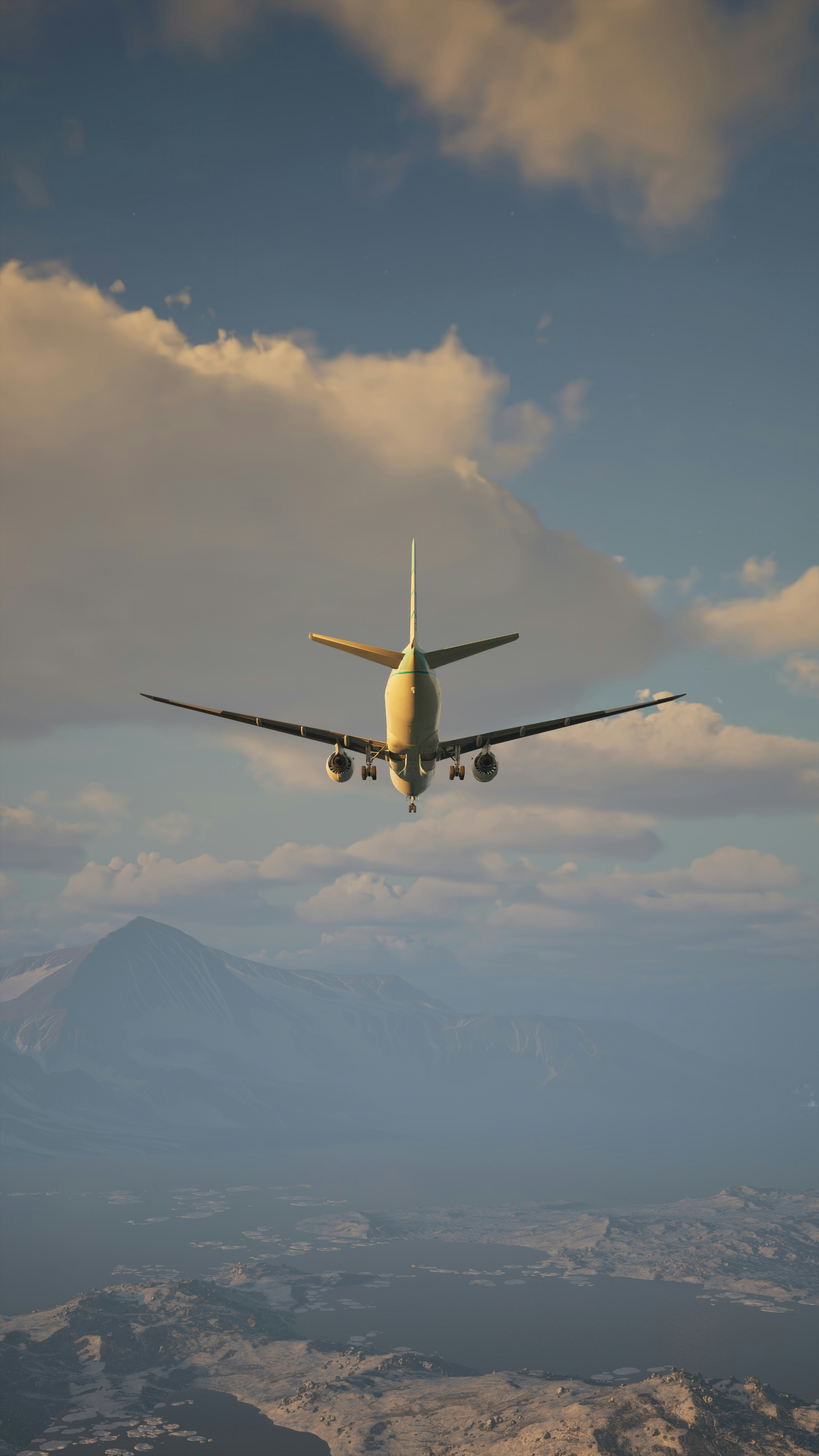 Airplane descending toward a mountain landscape at sunset.