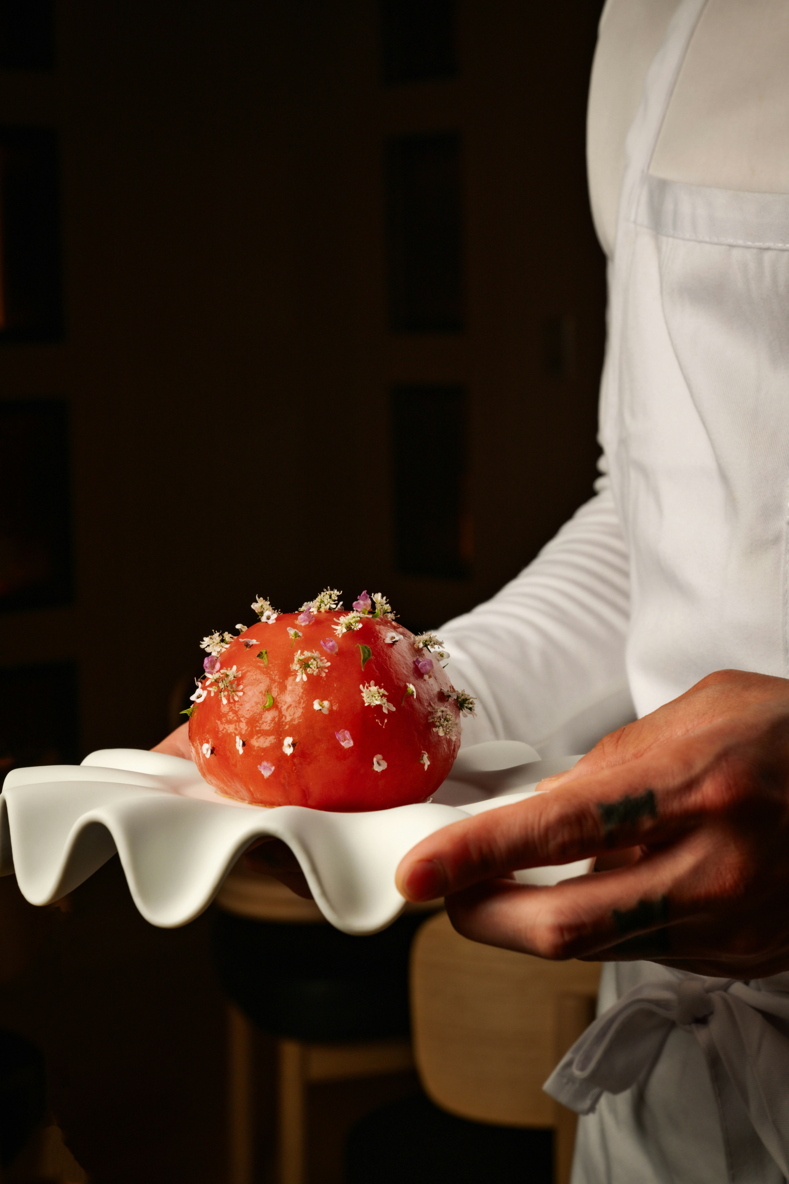 Chef presenting a dessert garnished with delicate edible flowers