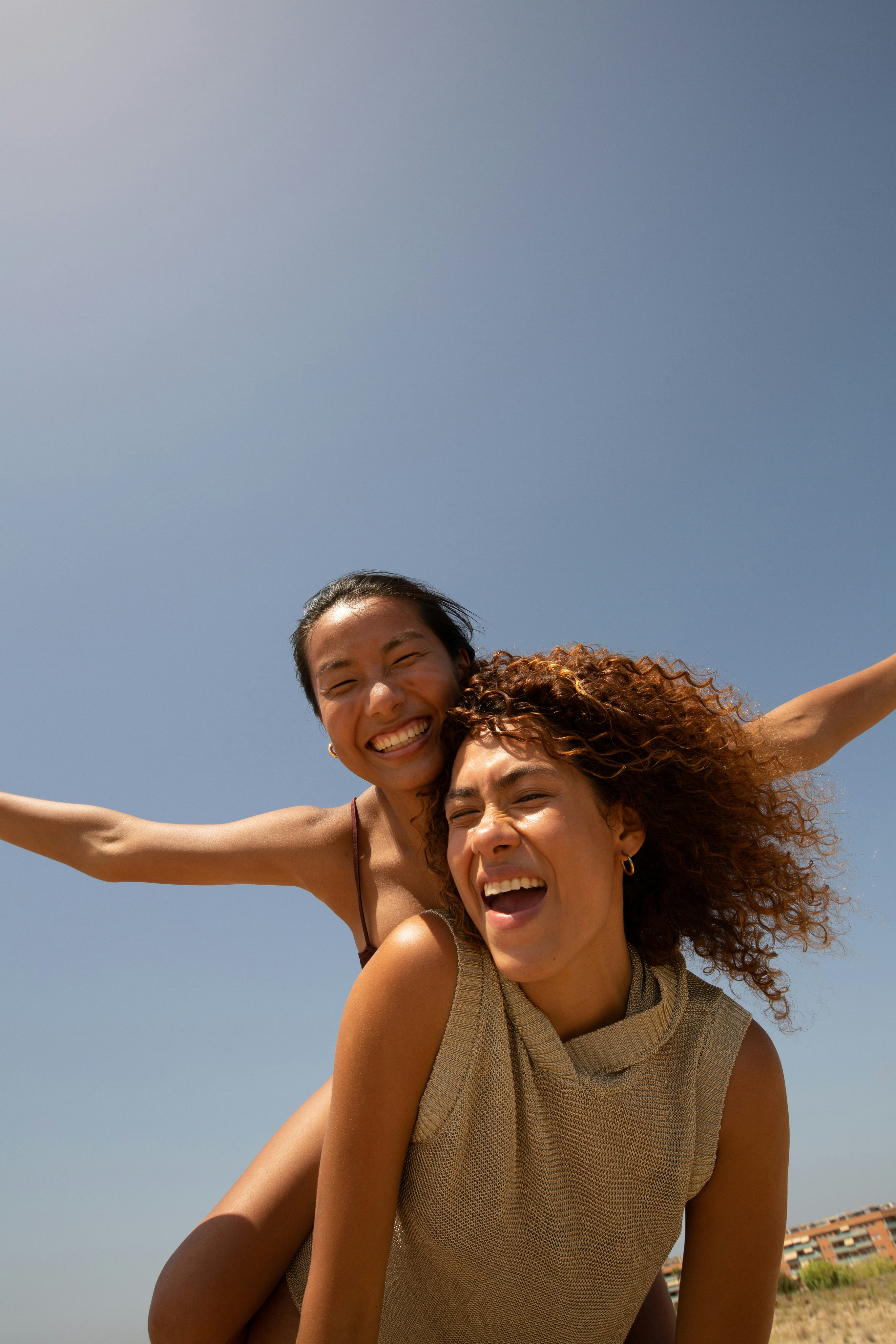Two women laughing together under the sun